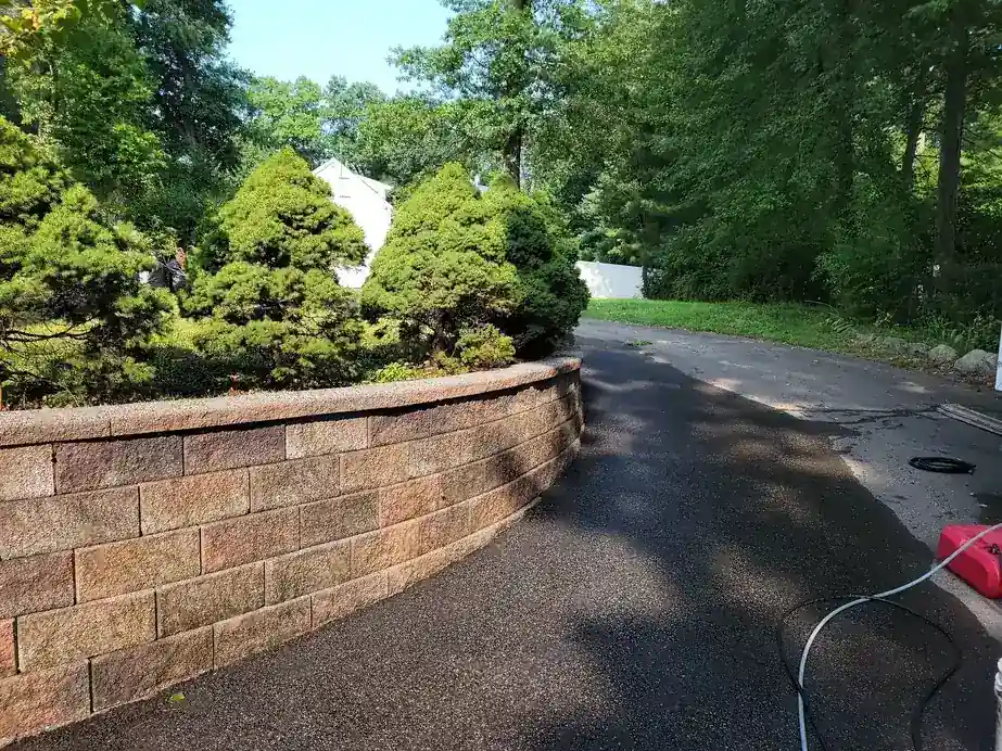 Block retaining wall along a freshly washed asphalt driveway